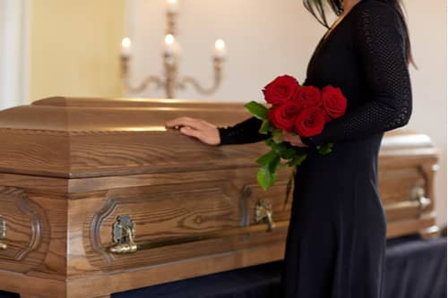 Woman holding roses at casket, Victorville wrongful death lawyer concept