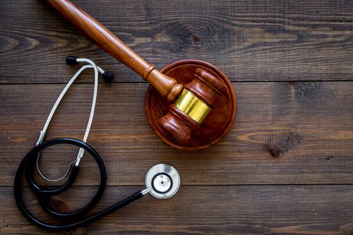 Image is of a stethoscope and gavel on a wooden table, concept of Fullerton personal injury lawyer