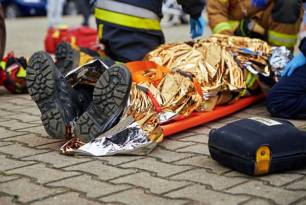 Rescuers provide first aid to the victim during a car accident. Person injured in the accident is lying on the road