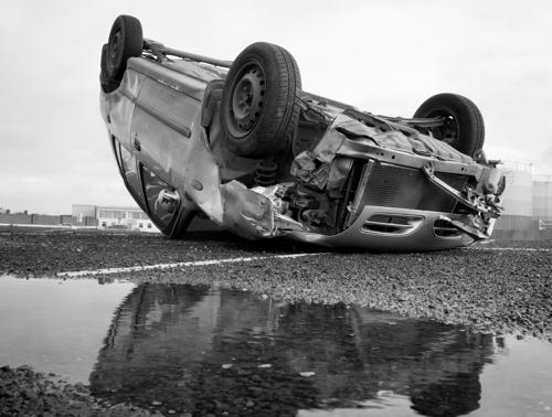 An upside-down car after a rollover accident on a freeway.