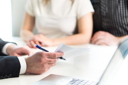 Image is of a couple sitting at a table discussing their case with a Fullerton car accident lawyer