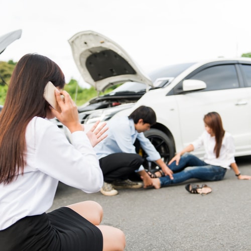 This is an image of a woman calling an Indio car accident lawyer at the scene of a crash with another hurt woman