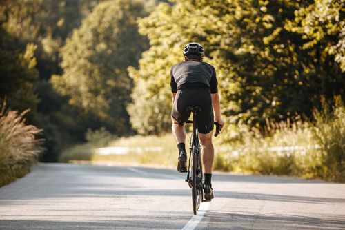 Man riding a bicycle on a rural road concept of Moreno Valley bicycle accident lawyer