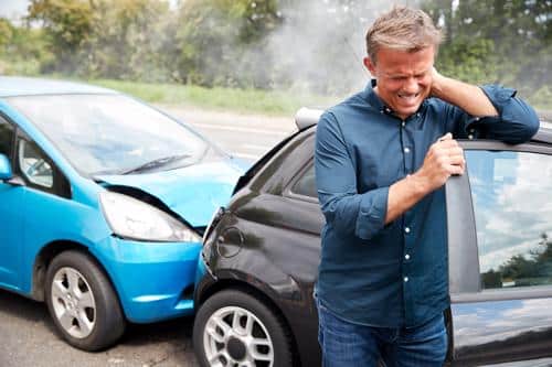 A man holding his injured neck after being rear-ended.