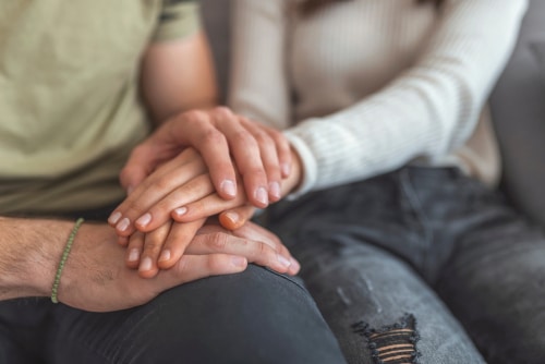 This is an image of a couple holding hands and mourning the loss of a loved one before calling a Joshua Tree wrongful death lawyer