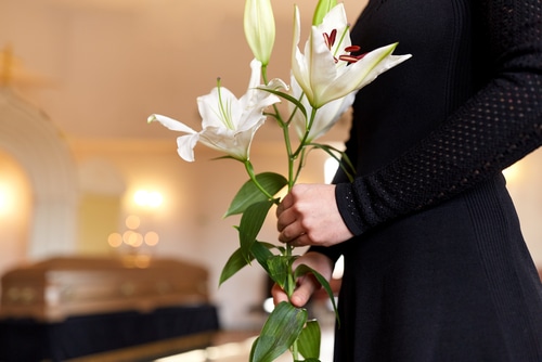 This is an image of a woman holding flowers next to a loved one's coffin who suffered wrongful death.